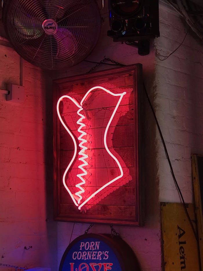 Neon corset sign on a brick wall adds a retro vibe to this dimly lit bar interior.